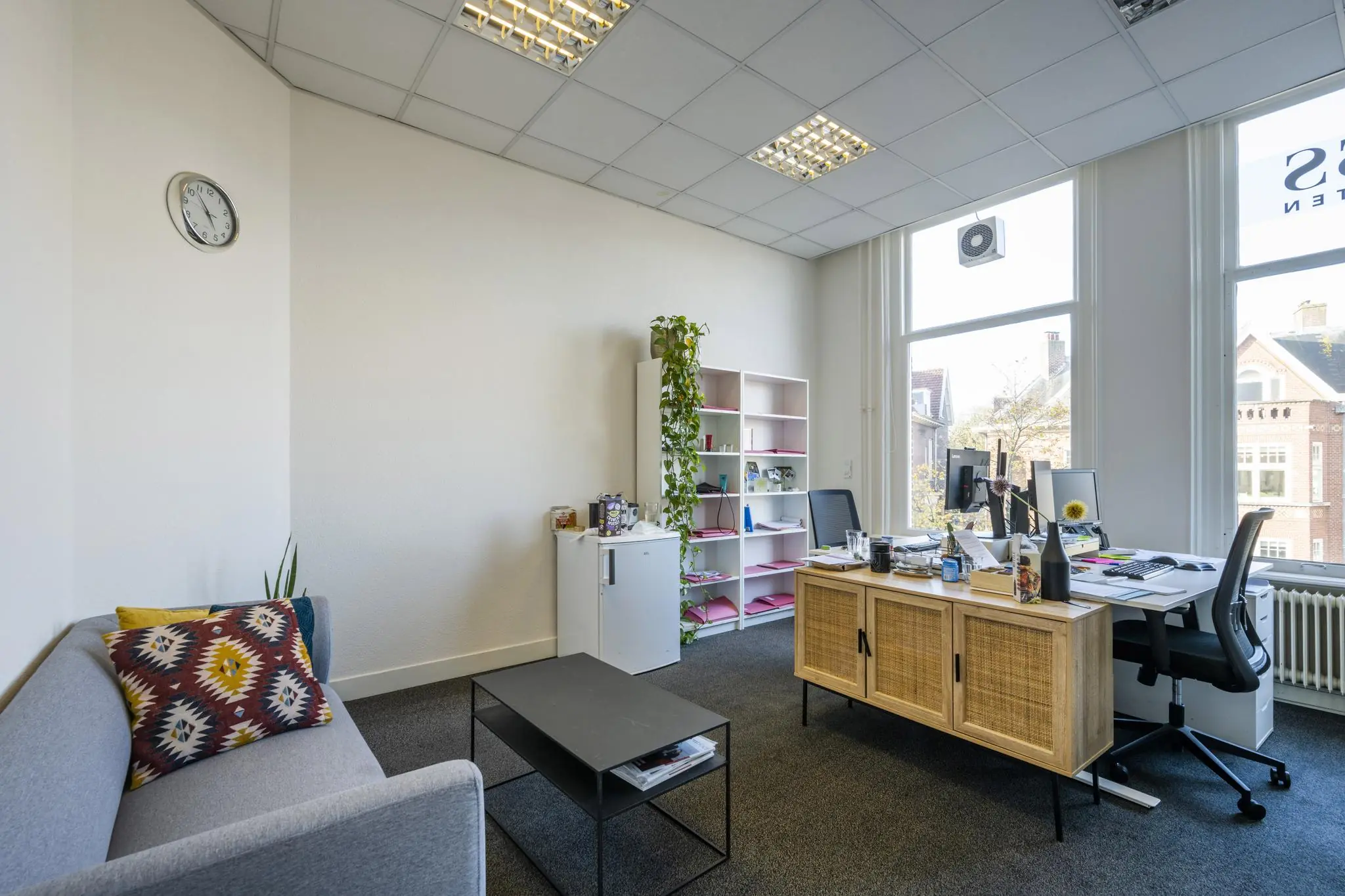 Modern kantoor aan de Van Eedenstraat met bureau, zitgedeelte en grote ramen met uitzicht op klassieke gevels.